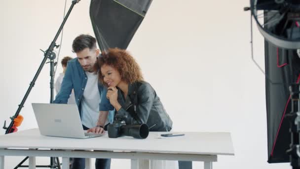 Photographer and model watching photos on laptop computer talking in studio — Stock Video