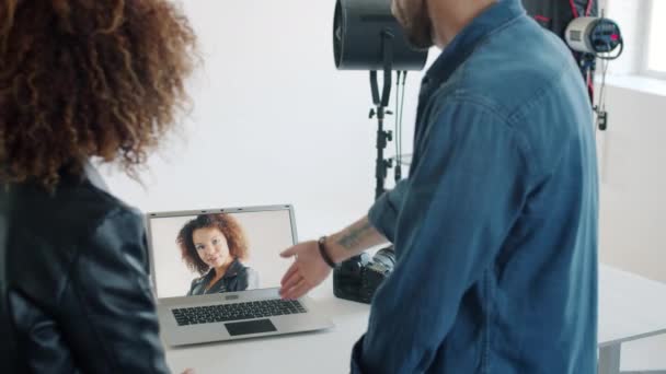 Modelo viendo nuevas fotos hablando con el fotógrafo en el estudio mirando la pantalla del ordenador portátil — Vídeos de Stock