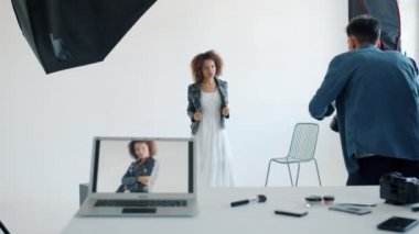 Stüdyoda fotoğrafçıyla fotoğraf çekilirken kameraya poz veren güzel genç bayan.