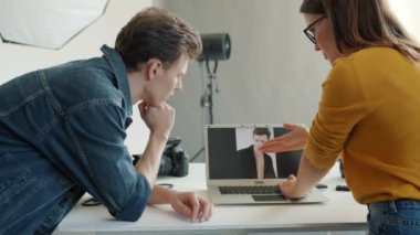 Kız ve erkeğin fotoğraf stüdyosunda dizüstü bilgisayardan fotoğraf izlediği arka plan görüntüsü