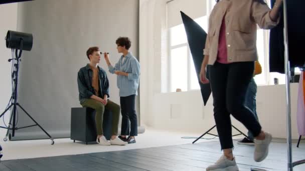 Mouvement lent du mannequin travaillant avec maquilleur, styliste et photographe en studio — Video