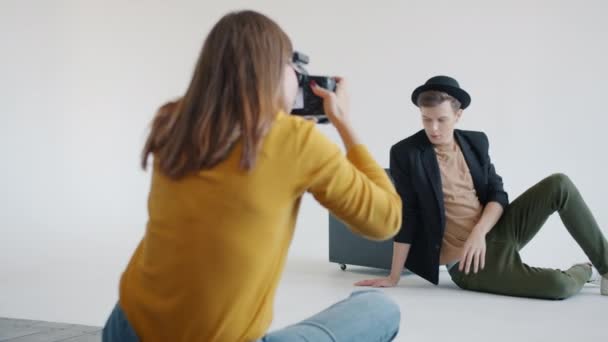 Cámara lenta de modelo y fotógrafo trabajando en el estudio durante la sesión de fotos — Vídeo de stock