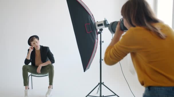 Movimento lento de modelo masculino atraente posando para fotógrafo em estúdio moderno — Vídeo de Stock