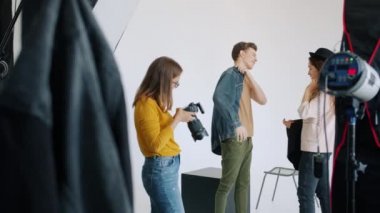 Moda giysileri giyen erkek model fotoğraf stüdyosunda stilistle çalışıyor.