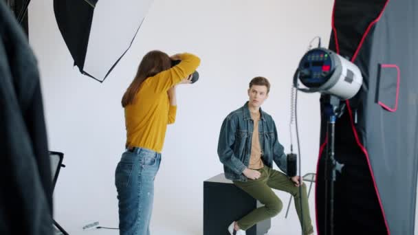 Cámara lenta de chico joven con ropa moderna posando para la cámara en el estudio — Vídeos de Stock