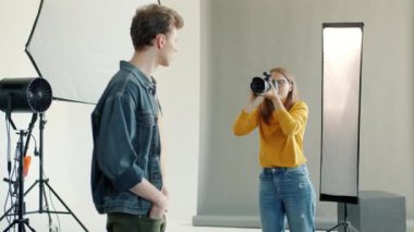 İçeride modelle çalışan fotoğrafçı kadının portresi. Kamerayla fotoğraf çekiyor.