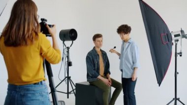 Çekici adam modeli vizeyle çalışıyor sonra da stüdyoda fotoğrafçıya poz veriyor.