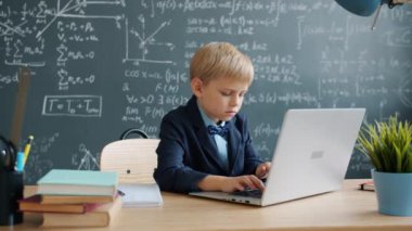 Genç dahi okulda dizüstü bilgisayarı tek başına kullanıyor. Çalışmaya odaklanmış.