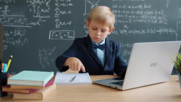 Σοβαρό μικρό αγόρι που χρησιμοποιεί υπολογιστή που σπουδάζει online στο σχολείο επικεντρώθηκε στην εκπαίδευση — Αρχείο Βίντεο