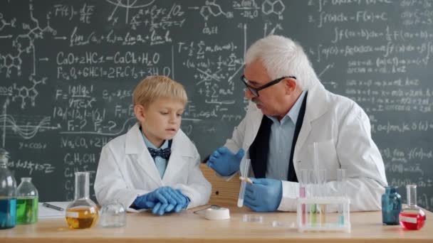 Pequeño estudiante y profesor discutiendo experimento de química en el aula — Vídeos de Stock