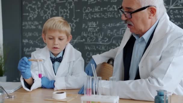 Schoolboy and teacher busy with chemical test in lab studying chemistry together — Stock Video