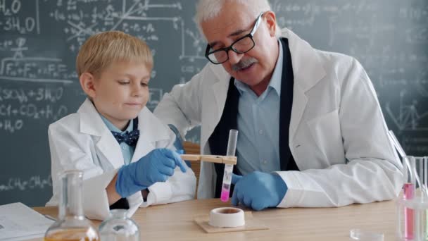 Χημικοί παιδί και δάσκαλος απασχολημένος με το πείραμα στο εργαστήριο χρησιμοποιώντας δοκιμαστικό σωλήνα και καυστήρα — Αρχείο Βίντεο