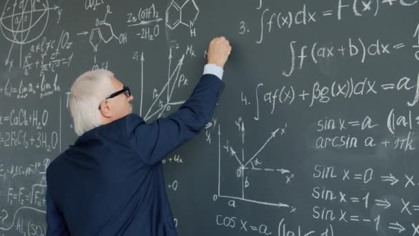 Mouvement lent du professeur d'université écrivant des formules sur tableau en classe — Video