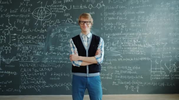 Portrait of cheerful guy standing in classroom smiling looking at camera with arms crossed — Stockvideo