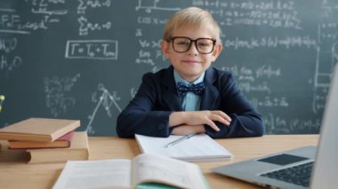 Üniversite sınıfında arka planda karatahta tahtası olan dahi çocuk yavaş hareket ediyor.