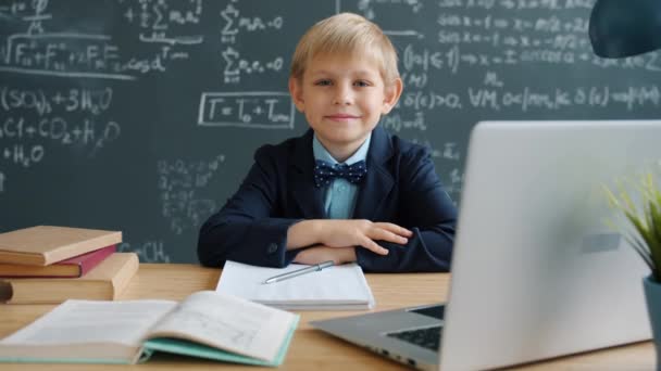 Mouvement lent de l'enfant heureux wunderkind en classe avec tableau plein de formules — Video