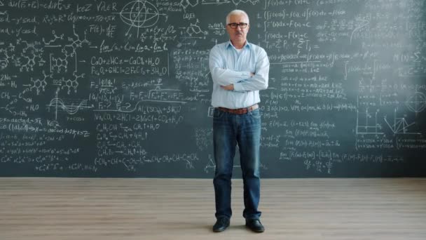 Slow motion portrait of serious mature scientist near clalkboard with formulas — Stockvideo