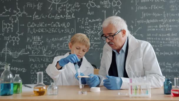 Αργή κίνηση έξυπνου αγοριού και ώριμου δασκάλου που διεξάγουν πειράματα στην τάξη χημείας — Αρχείο Βίντεο