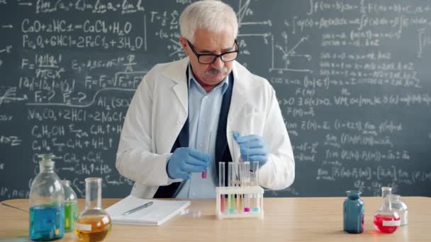 Doświadczony chemik robi badania chemiczne, a następnie zapisuje wyniki pracy w laboratorium. — Wideo stockowe