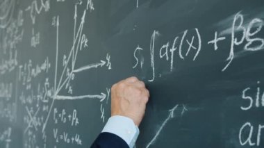 Slow motion of male hand underlining maths equation on chalkboard in class