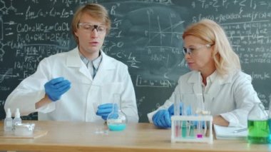 Slow motion of serious people man and woman doing chemical experiment in classroom