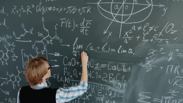 High angle view of mathematics teacher writing formulas and equations on board — Stok video