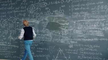 Time lapse of creative guy researcher writing formulas on chalkboard in class