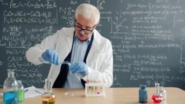 Mature man scientist conducting chemical test in laboratory taking notes
