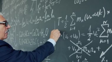 Portrait of elderly man college teacher underlining formula on chalkboard writing