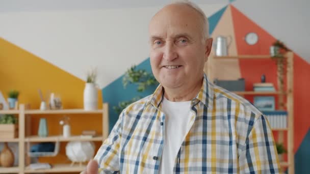 Портрет красивого літнього чоловіка, що показує жест руки в квартирі — стокове відео