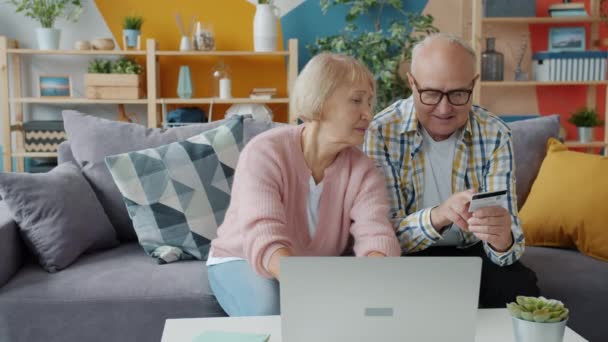 Suami dan istri senior melakukan pembayaran elektronik dengan kartu bank dan laptop — Stok Video