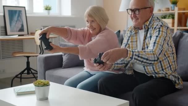 Медленное движение счастливых стариков, играющих дома в видеоигры и наслаждающихся весельем — стоковое видео