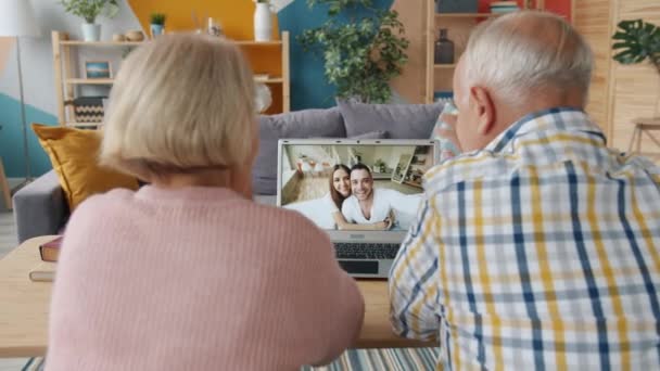 Couple retraité faisant un appel vidéo en ligne parler aux jeunes de la famille de la maison — Video