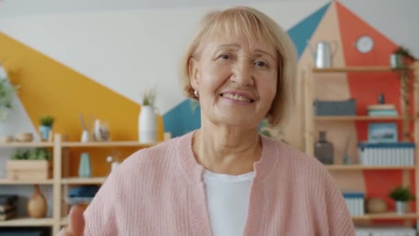 Retrato en cámara lenta de una mujer mayor mostrando un gesto de la mano con los pulgares hacia arriba sola en casa — Vídeos de Stock
