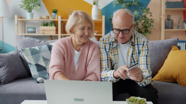 Orang tua yang ceria melakukan pembayaran online dengan kartu bank menggunakan laptop di rumah — Stok Video