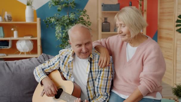 Lassú mozgás az idős férfi gitározik, és énekel élvezi a szabadidőt a feleségével — Stock videók