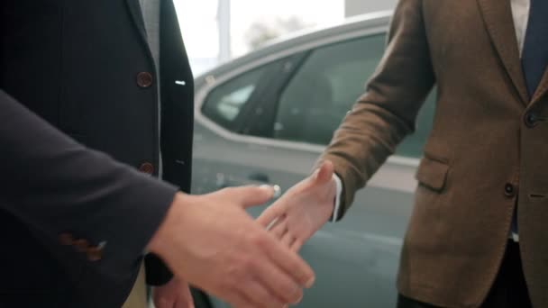 Movimiento lento de apretón de manos, el cliente masculino compra de coches en la sala de exposición tomando llaves — Vídeo de stock