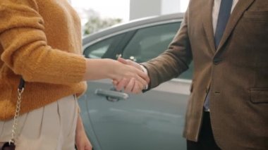 Slow motion of male and female hands shaking taking and giving keys in car dealership