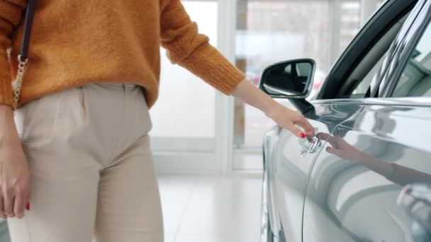 Крупный план женщины-покупателя, открывающей дверь автомобиля, выбирающей автомобиль в автосалоне — стоковое видео