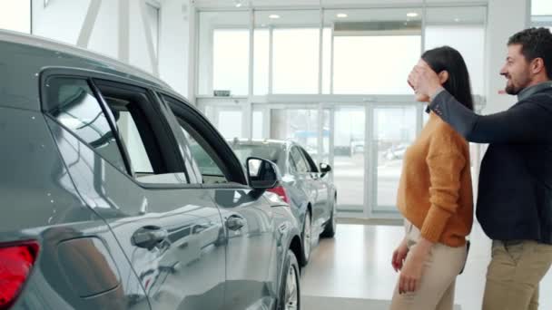 Loving husband giving car to beloved wife as a surprise in motor showroom — Stock Video