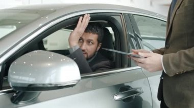 Good-looking man buyer talking to sales manager sitting in car touching shiny auto
