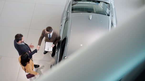 Vista de ángulo alto de la familia joven comprando coche estrechando la mano con el vendedor abrazo — Vídeo de stock