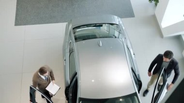 High angle view of men sales manager and customer sitting in car in dealership