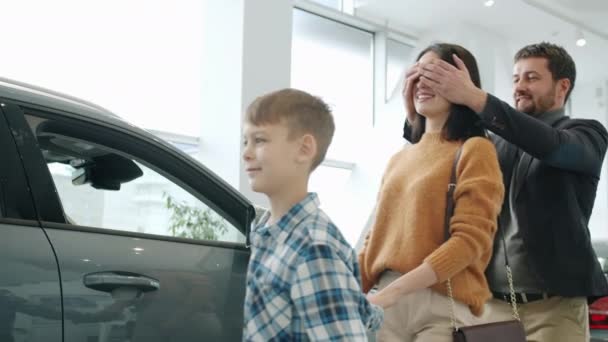 Медленное движение радостной леди, получающей машину в подарок от мужа и сына, обнимающего смех — стоковое видео