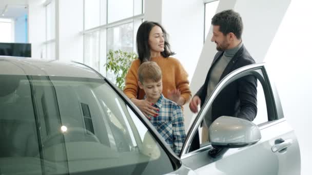 Мати, батько і син купують машину, роблячи п'ять, насолоджуючись новим авто в шоу-румі — стокове відео