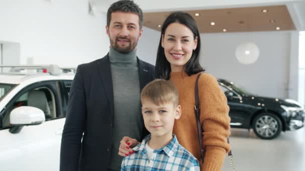 Portrait of cheerful people parents and kid standing together in automobile showroom — Stockvideo