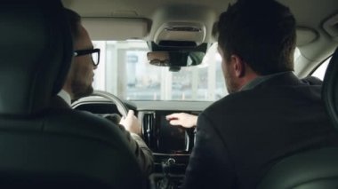 Young businessman discussing car with professional salesman s inside luxury automobile