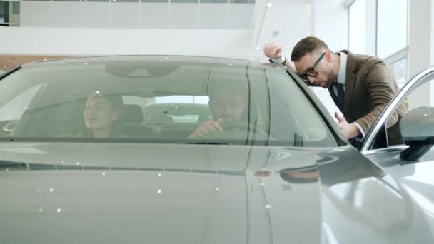 Distribuidor de coches profesional hablando con pareja joven compra de automóviles en la concesionaria — Vídeos de Stock