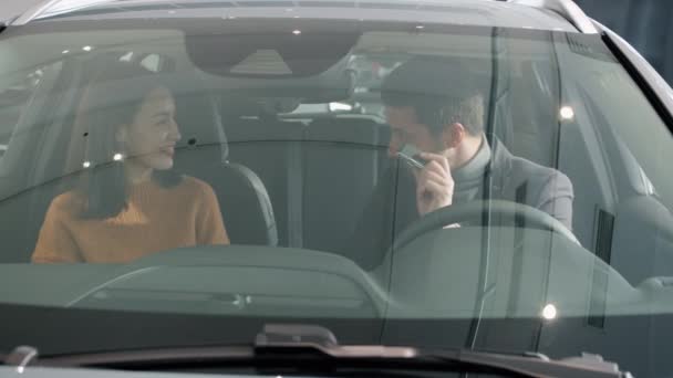 Женщина получает ключи от машины, хлопая в ладоши, обнимая мужчину, сидящего внутри новой машины — стоковое видео