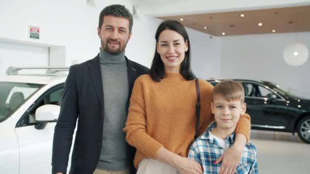 Slow motion of happy family with son smiling in car dealership standing together — Stock Video